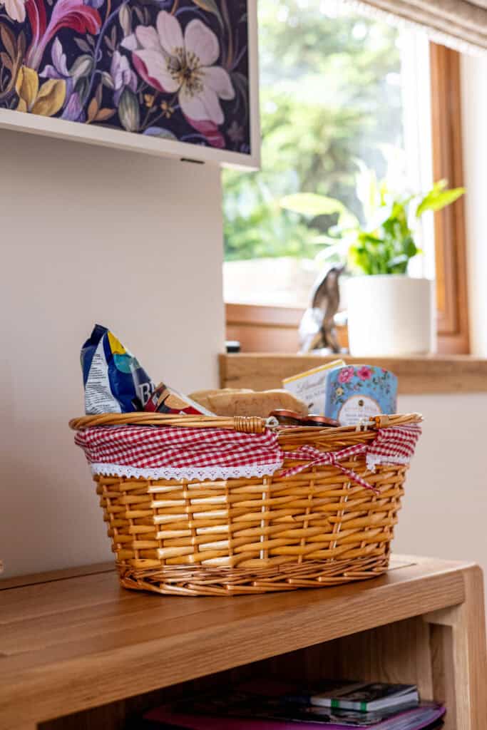 Wicker basket with snacks on wooden table.