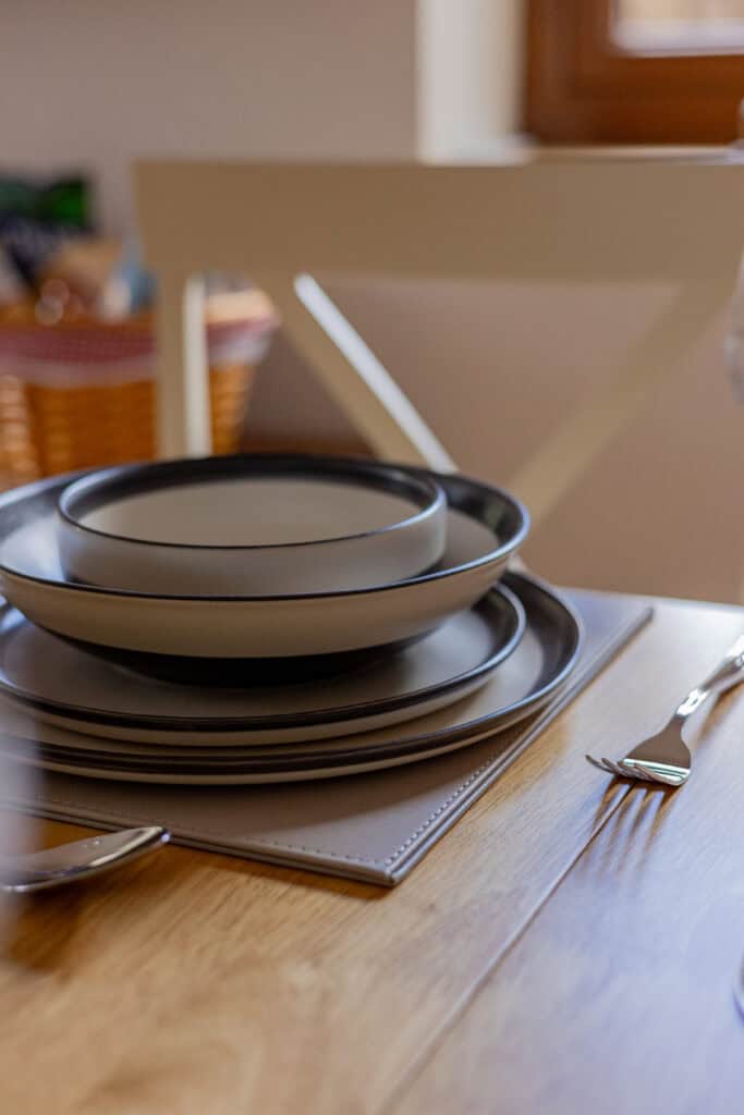 Stacked grey plates with spoon on wooden table.