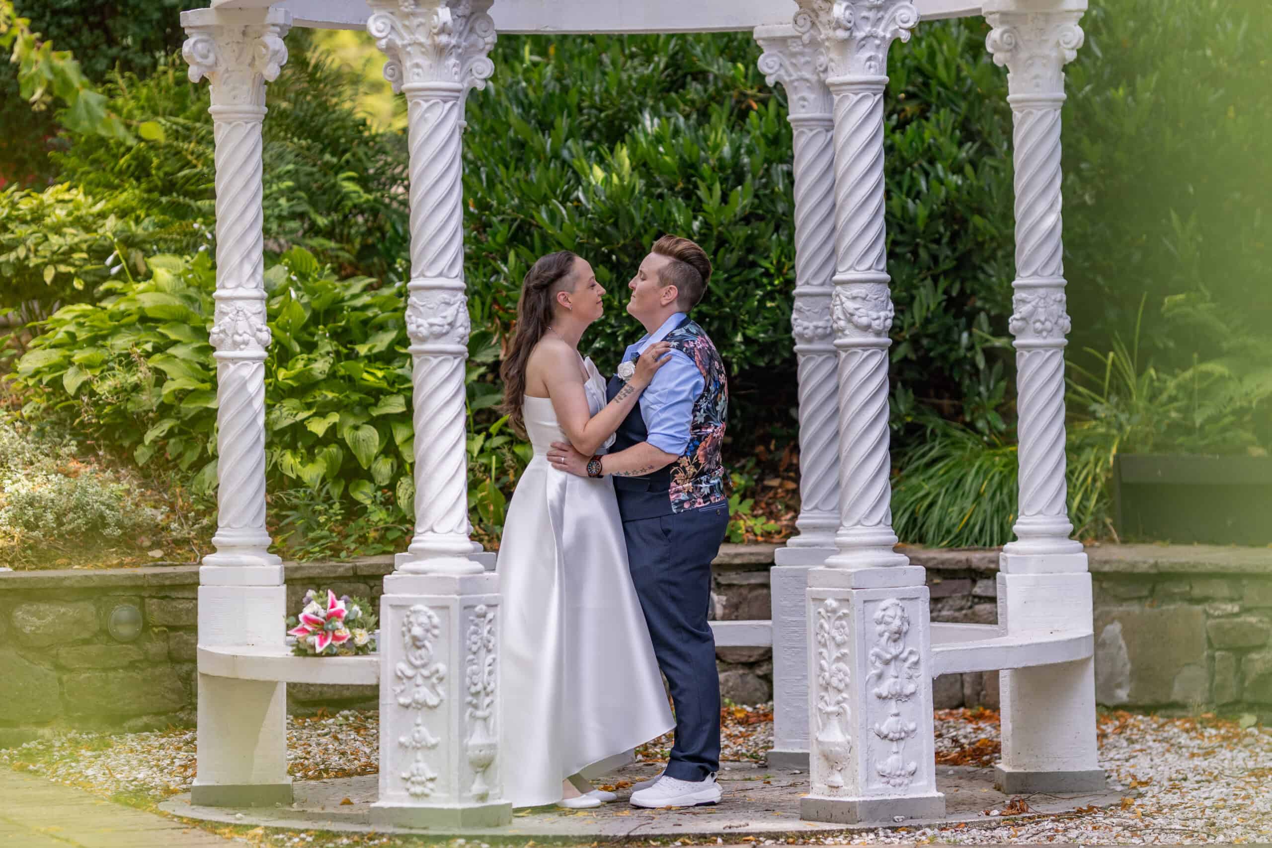Couple embracing under garden gazebo.