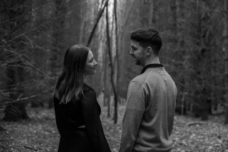 Couple smiling in a forest during autumn.