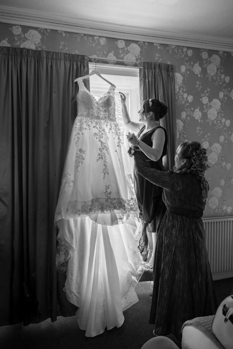 Women adjusting a wedding dress by window