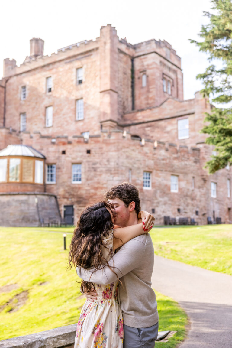 Couple kissing outside a historic stone castle