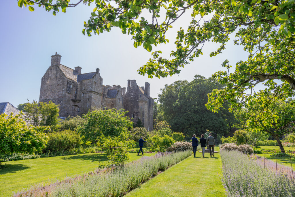 Historic stone Kellie Castle, Fife, sits beside manicured gardens on a sunny day.