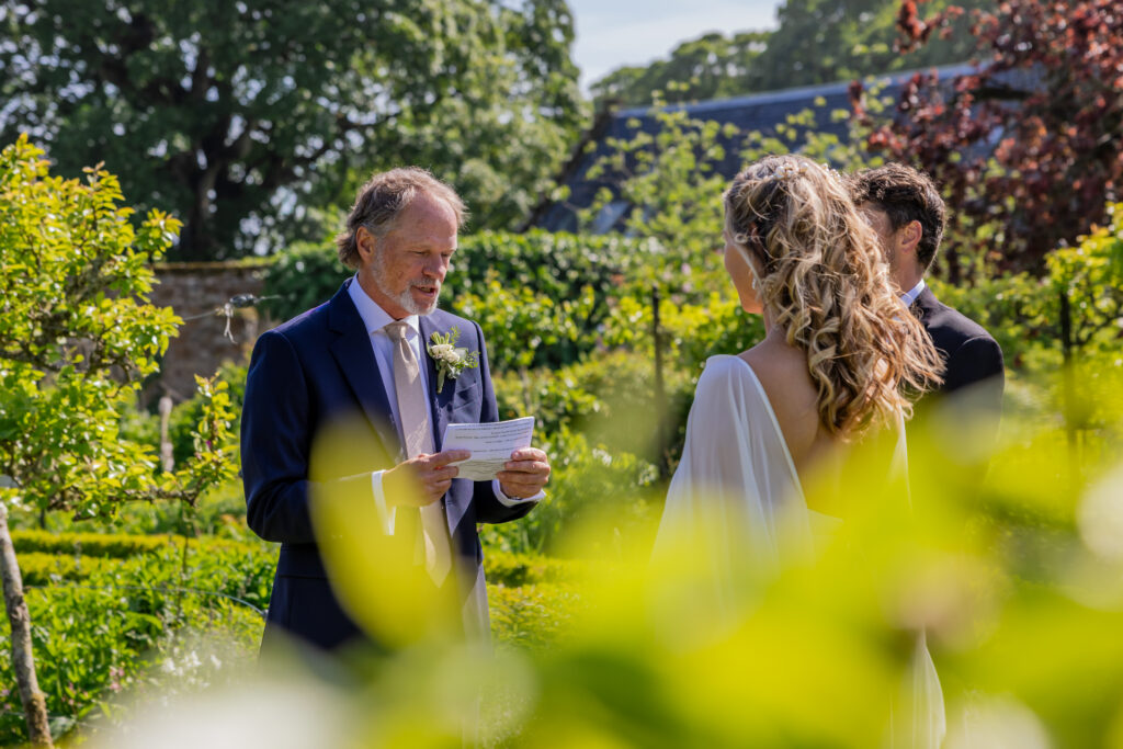 Groom reads his personal vows during a sunny garden wedding ceremony at Kellie Castle, Fife, Scotland.