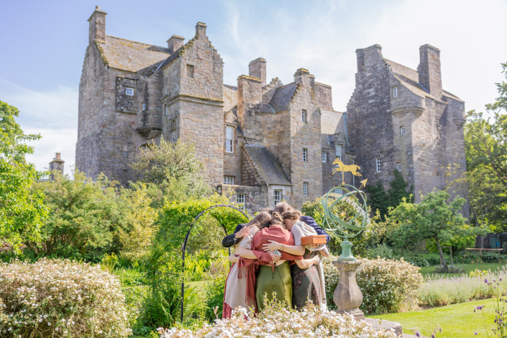 Friends embrace beside sundial in historic castle garden