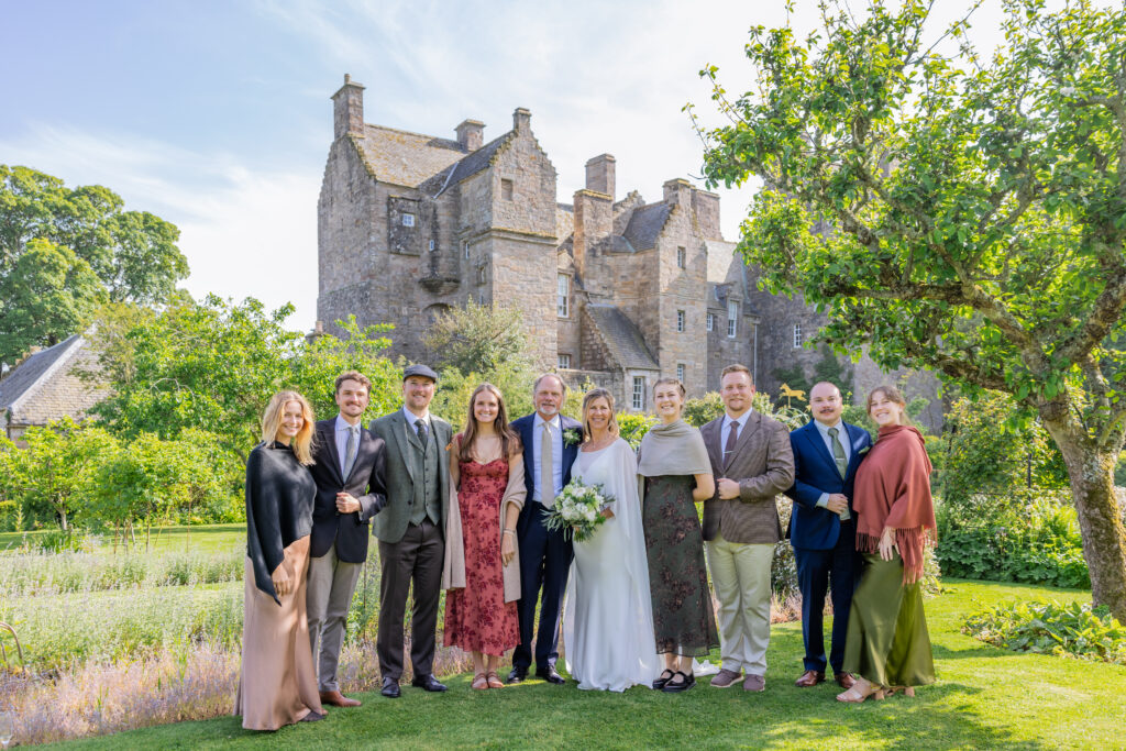 Wedding party posing before a historic stone castle