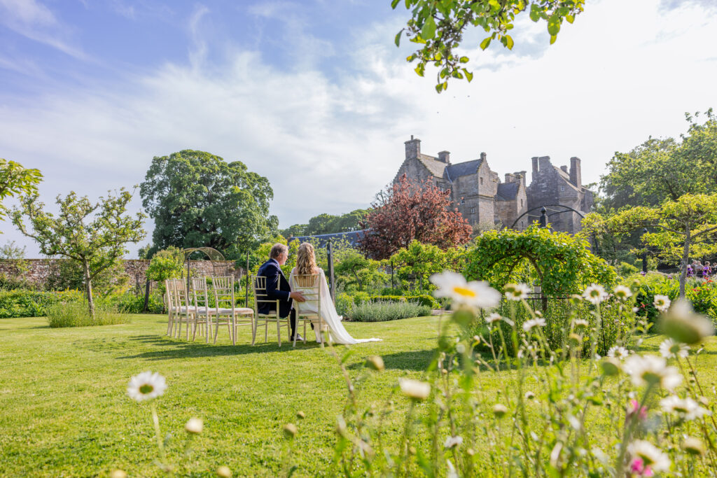 Newlyweds seated in a castle garden wedding ceremony