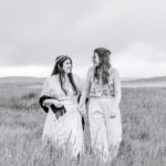 Two women holding hands in a grassy field