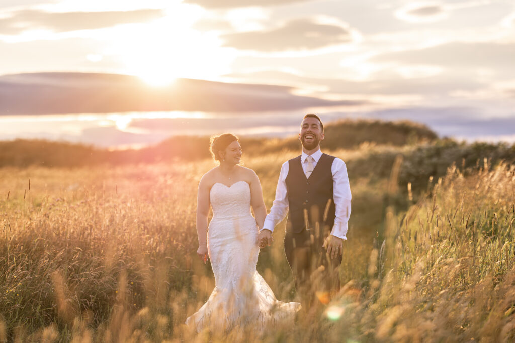 Newlyweds holding hands in a sunlit meadow