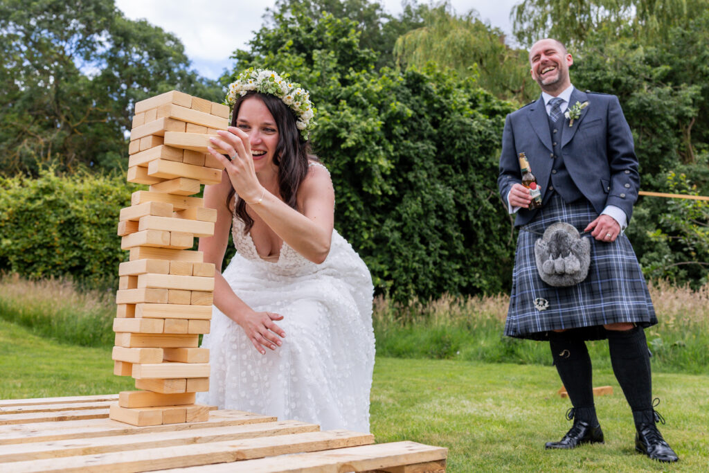 Bride plays giant Jenga as groom laughs outdoors