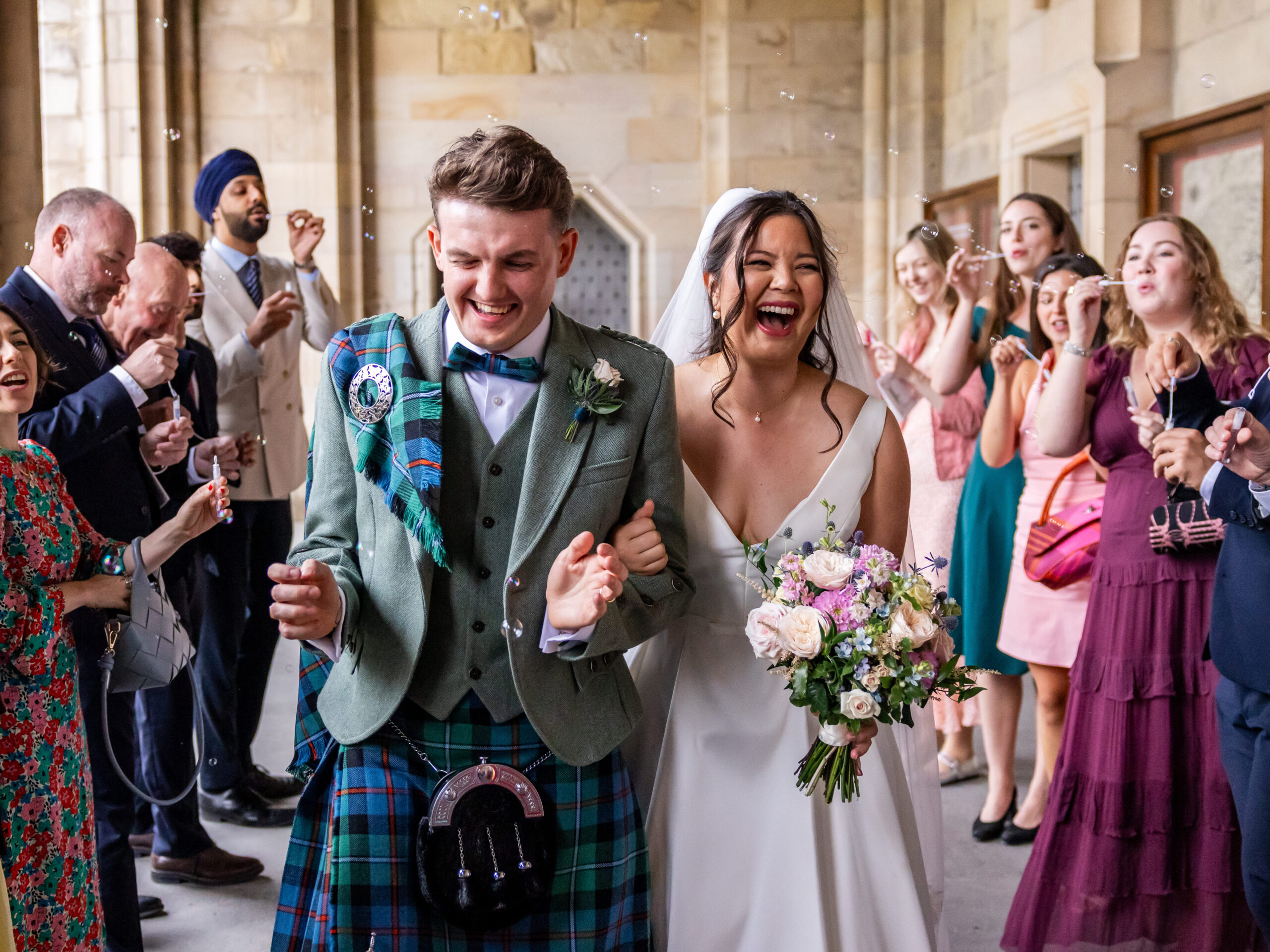 Newlyweds in Scottish tartan celebrate beneath wedding bubbles